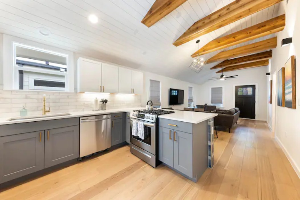 2319 Santa Rita Street Austin, TX 78702 - Photo 24 of 26 Kitchen with two tone color scheme, a peninsula, stainless steel appliances, open floor plan, and light wood finished floors