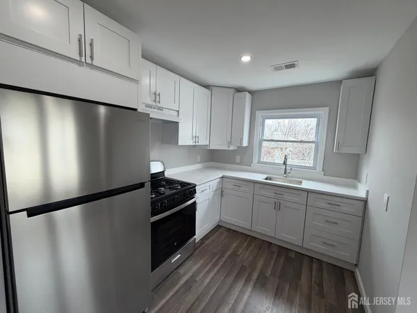 a kitchen with granite countertop a refrigerator sink and cabinets