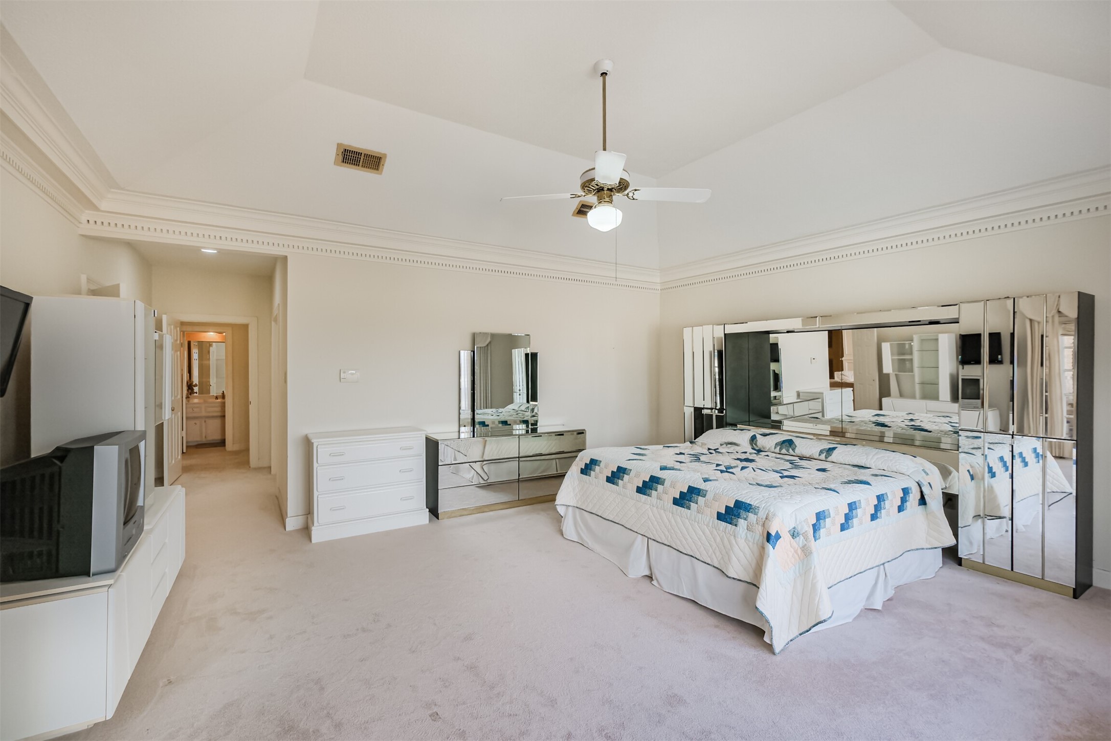 32726 Weybridge Street Fulshear, TX 77441 - Photo 29 of 50 a spacious bedroom with a large bed a flat tv screen and a dresser