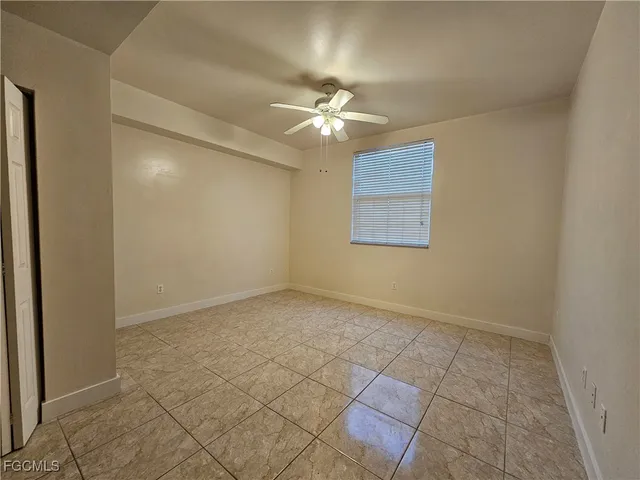 an empty room with a ceiling fan and a window