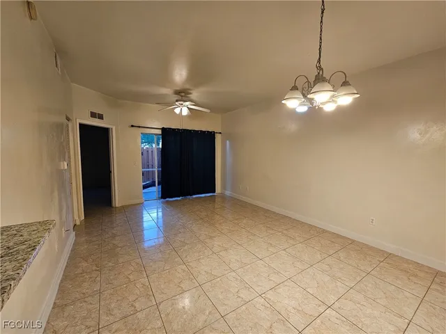 a view of a livingroom with a chandelier fan and kitchen area