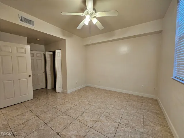 an empty room with a ceiling fan and carpet