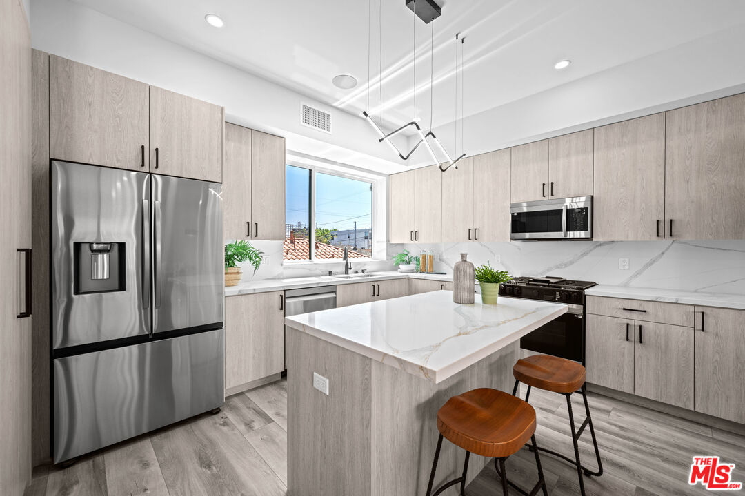 1959 Preuss Road Los Angeles, CA 90034 - Photo 6 of 29 a kitchen with stainless steel appliances a refrigerator stove microwave and white cabinets