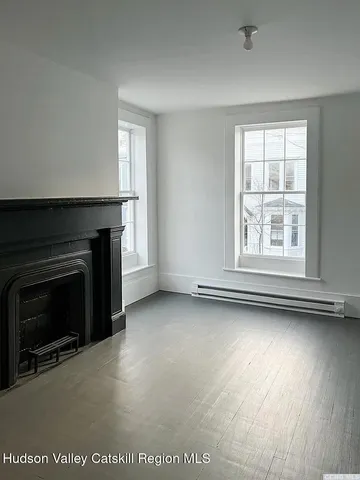 an empty room with windows fireplace and wooden floor