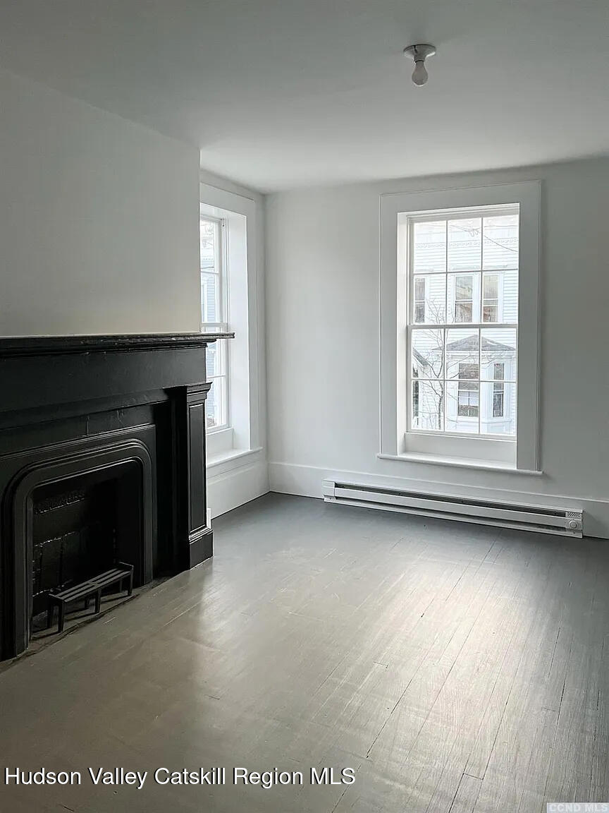 30 Union Street, Unit 2 Hudson, NY 12534 - Photo 6 of 10 an empty room with windows fireplace and wooden floor