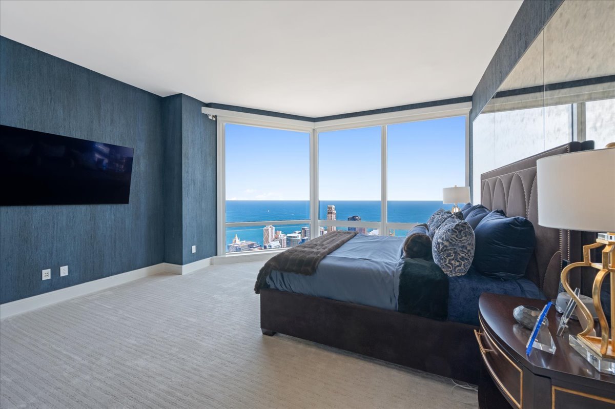 401 North Wabash Avenue, Unit 73F Chicago, IL 60611 - Photo 8 of 40 a bedroom with a bed a couch and a flat screen tv