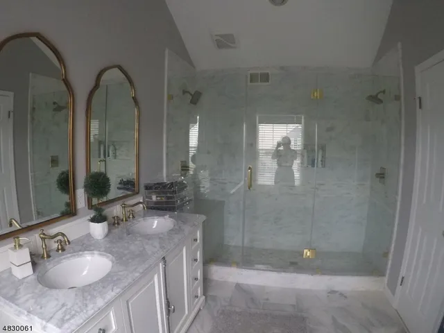 a bathroom with a granite countertop sink a mirror and shower
