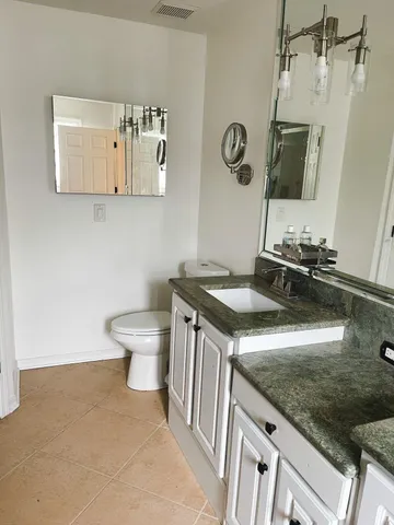 a bathroom with a granite countertop toilet sink and mirror