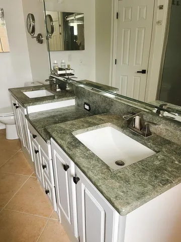 a bathroom with a granite countertop sink and a mirror
