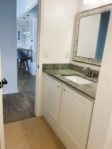 a en suite bathroom with a granite countertop sink and a mirror