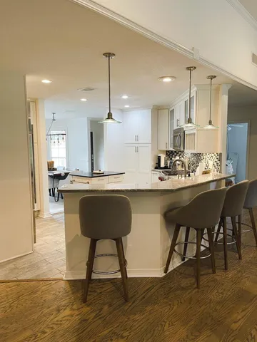 a kitchen with a dining table chairs and wooden floor