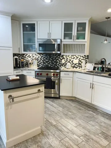 a kitchen with stainless steel appliances granite countertop a sink stove and cabinets