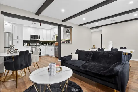 a living room with stainless steel appliances furniture and a kitchen view