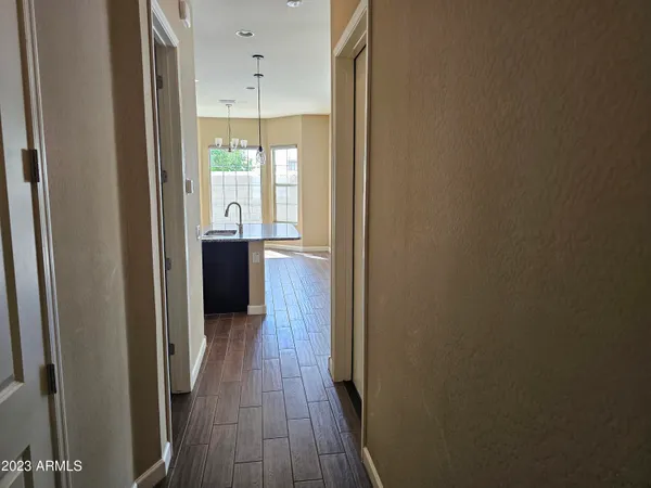 a view of a hallway with wooden floor and a bathroom