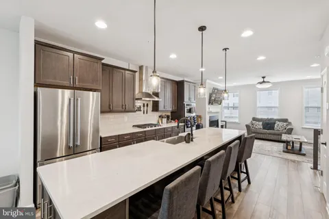 a kitchen with stainless steel appliances a table chairs refrigerator and wooden floor
