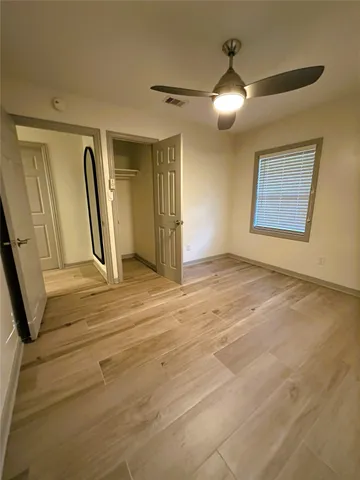 an empty room with wooden floor and a ceiling fan