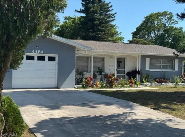a front view of house with yard and trees in the background
