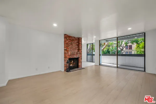 a view of an empty room with a fireplace and window