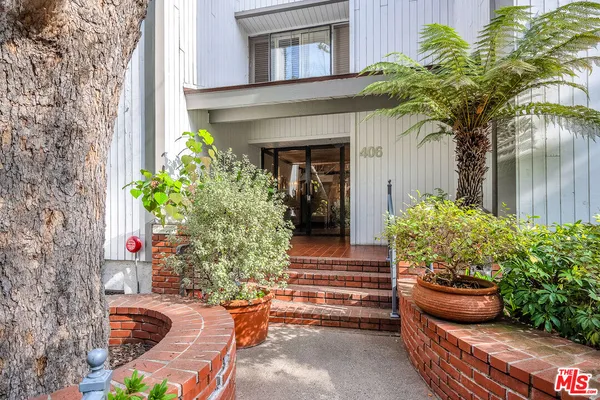 a view of a house with potted plants and a fountain