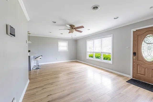 a view of an empty room with a window and wooden floor