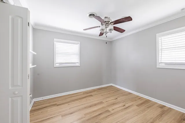 a view of an empty room with wooden floor and a window