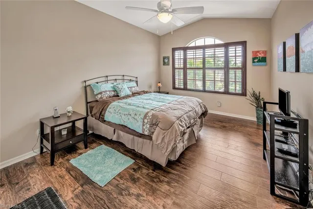 a bedroom with a bed table and two window