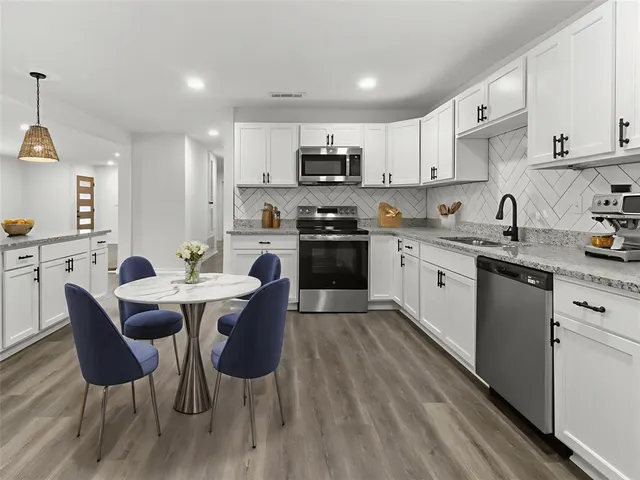 a kitchen with stainless steel appliances granite countertop a table chairs sink refrigerator and cabinets