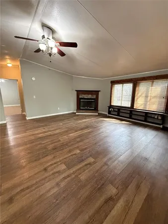 an empty room with wooden floor chandelier and windows