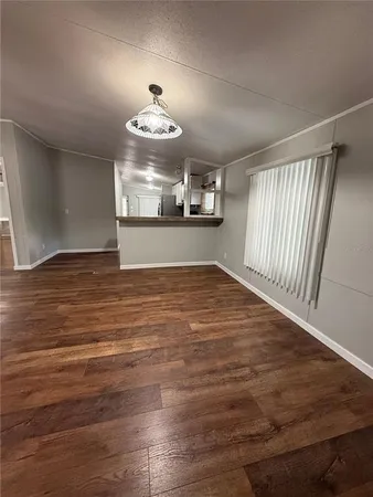 an empty room with wooden floor chandelier fan and windows