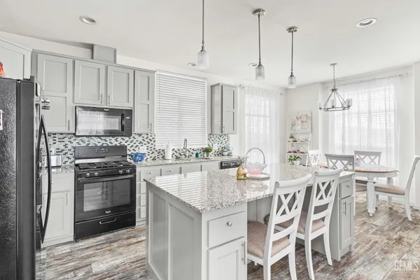 a kitchen with stainless steel appliances granite countertop a table chairs stove and white cabinets