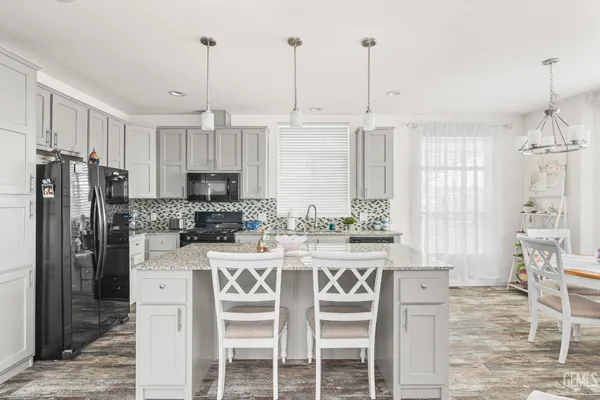 a kitchen with stainless steel appliances granite countertop a stove a refrigerator a oven a sink with a dining table and chairs