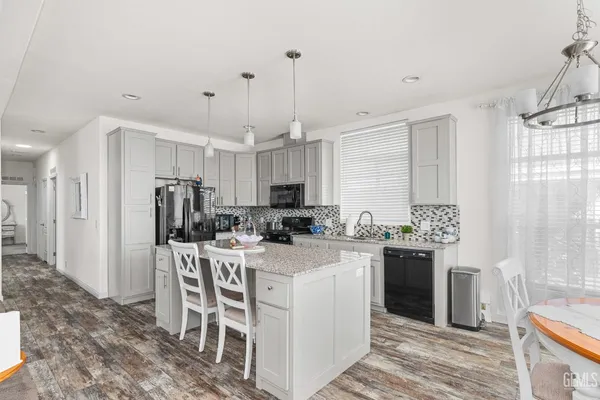 a kitchen with a refrigerator a stove a sink a dining table and chairs