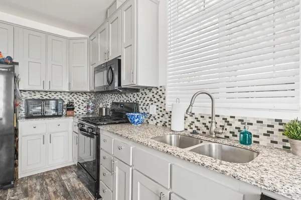 a kitchen with granite countertop a sink a stove and cabinets