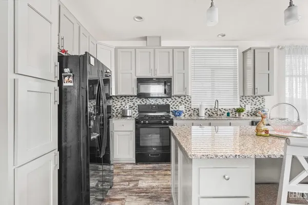 a kitchen with granite countertop a refrigerator stove and sink