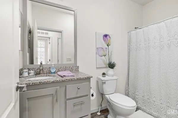 a bathroom with a granite countertop sink mirror vanity and toilet