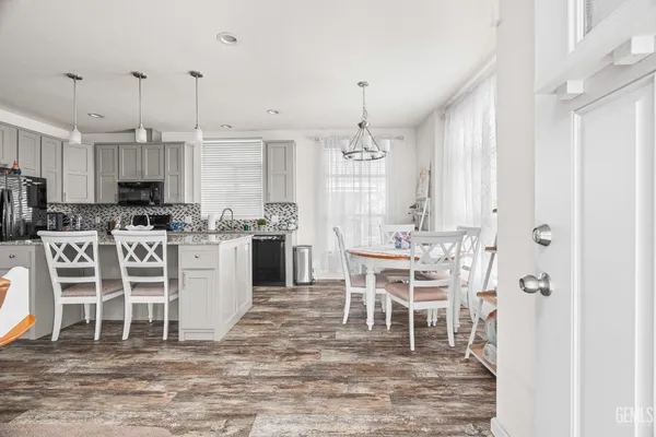 a dining room with furniture a chandelier and kitchen view