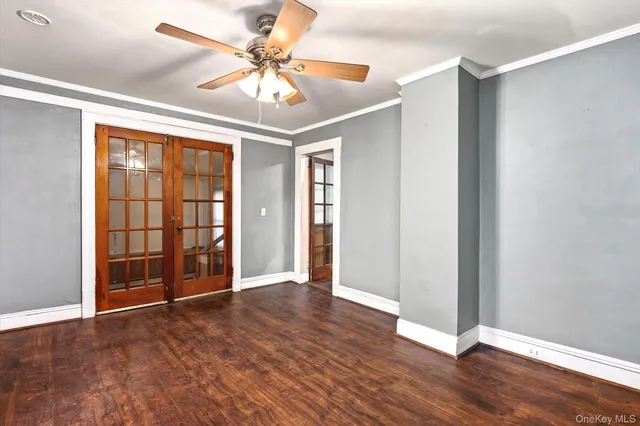an empty room with wooden floor chandelier fan and windows