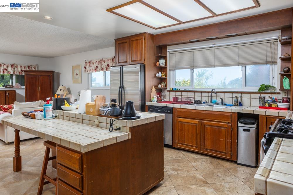 4591 Edwards Lane Castro Valley, CA 94546 - Photo 8 of 44 a kitchen with stainless steel appliances kitchen island granite countertop a table chairs in it and wooden floors