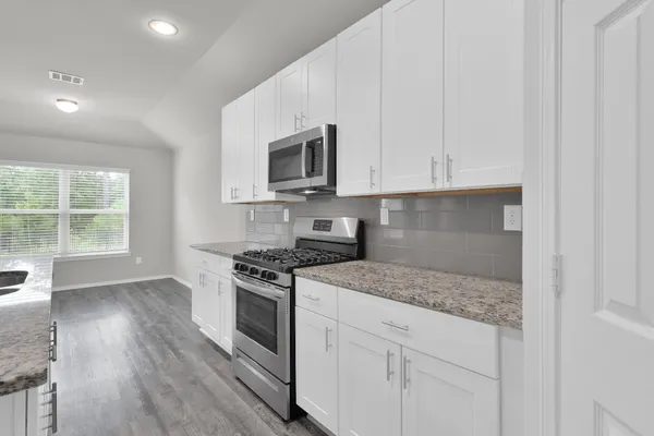 a kitchen with granite countertop white cabinets and appliances