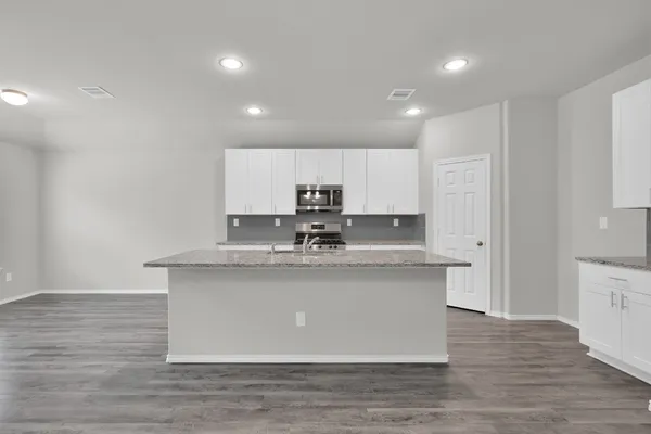 a kitchen with stainless steel appliances granite countertop a sink a stove a refrigerator and white cabinets