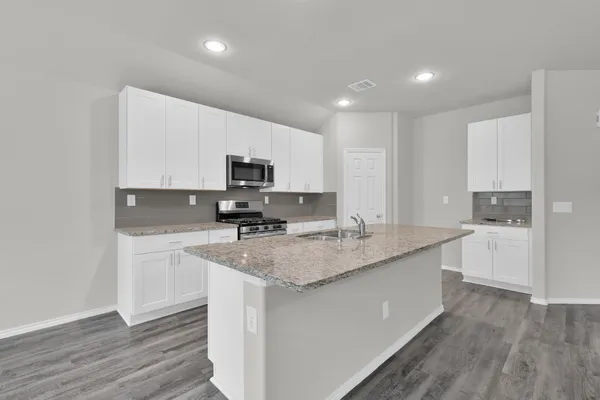 a kitchen with stainless steel appliances granite countertop a sink dishwasher a stove top oven a refrigerator with white cabinets and wooden floor