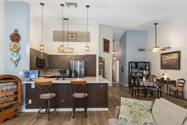 a view of a dining room and livingroom with furniture wooden floor a rug a painting and a chandelier