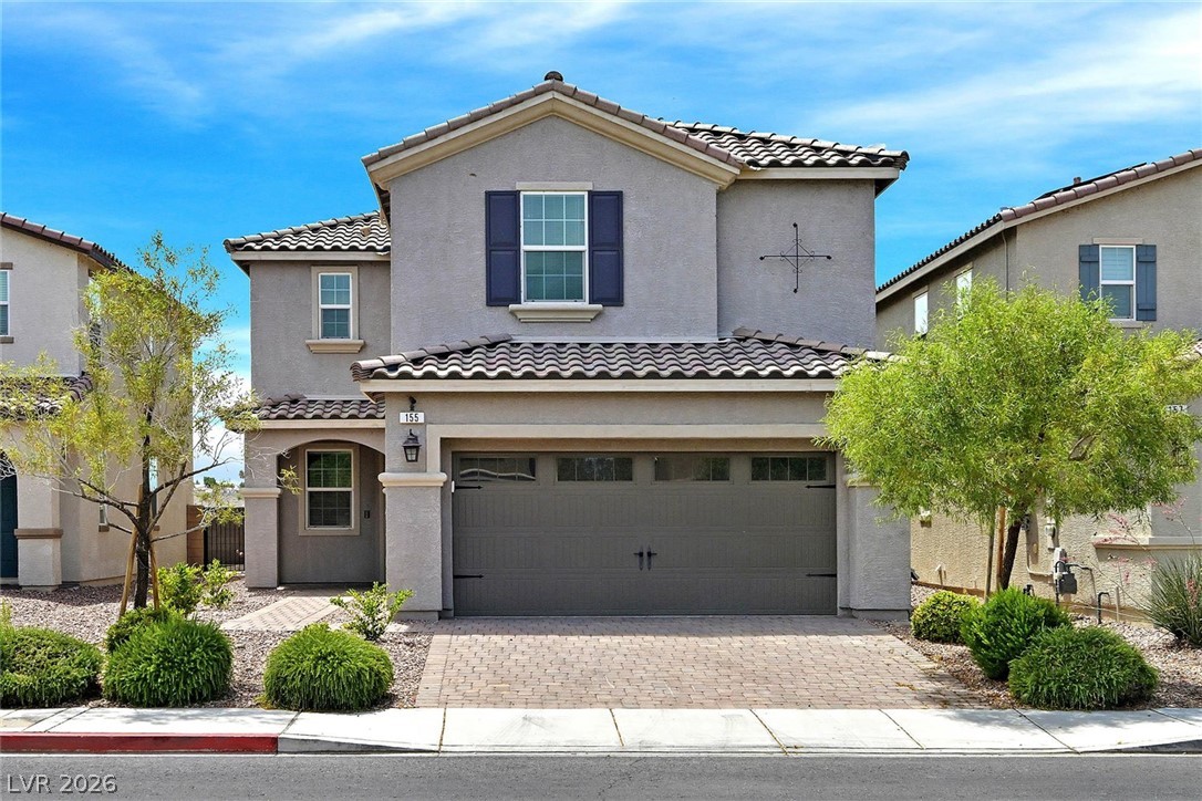 A classic stucco home with a tile roof offers a welcoming entrance and ample parking.