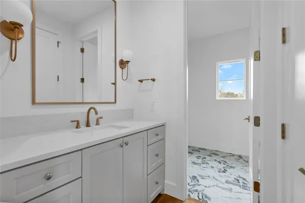 a bathroom with a toilet a sink a mirror and a window