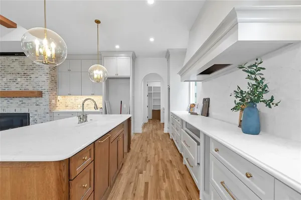 a large kitchen with stainless steel appliances wooden floors and white cabinets