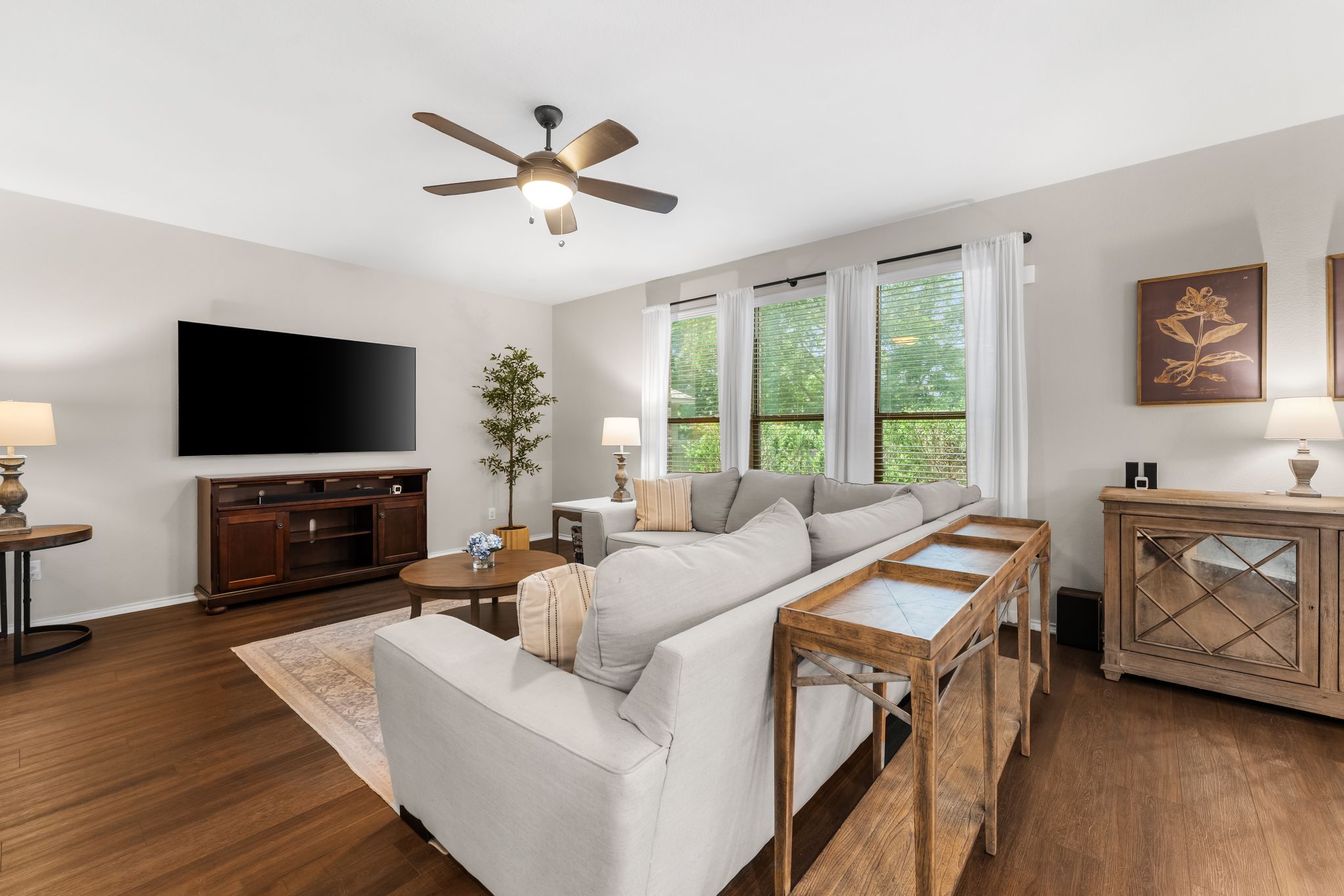 1133 Yellow Iris Road Leander, TX 78641 - Photo 10 of 37 Spacious living area featuring wood-finish flooring, ample natural light from multiple windows, a ceiling fan with integrated lighting, and neutral wall tones