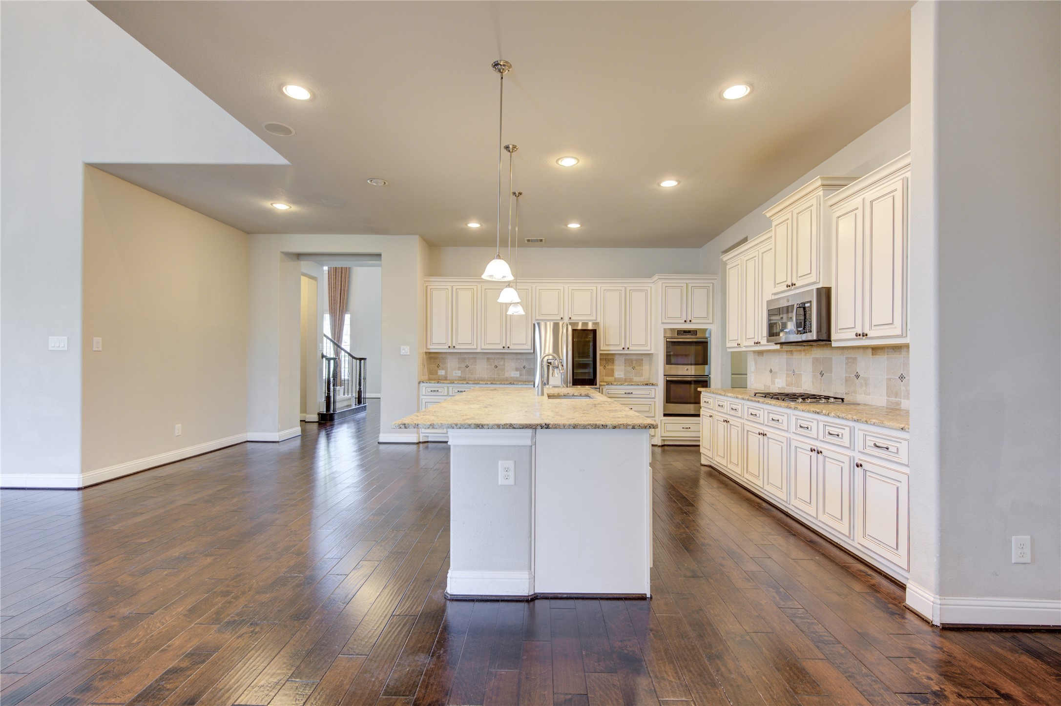 20411 Fawn Rest Place Spring, TX 77379 - Photo 25 of 50 a large kitchen with stainless steel appliances granite countertop a large center island a sink dishwasher a refrigerator and white cabinets with wooden floor