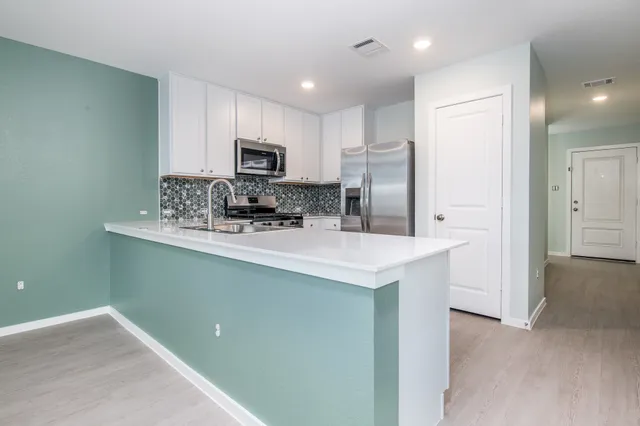 a kitchen with kitchen island a sink stainless steel appliances and cabinets
