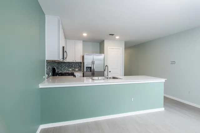 a view of kitchen island with stainless steel appliances granite countertop refrigerator sink and stove