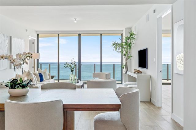 a dining room with furniture a potted plant and a large window